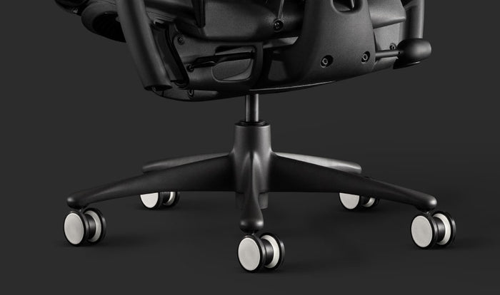 Gros plan d'un fauteuil de jeu Embody noir de Herman Miller, montrant les roulettes noires et blanches.