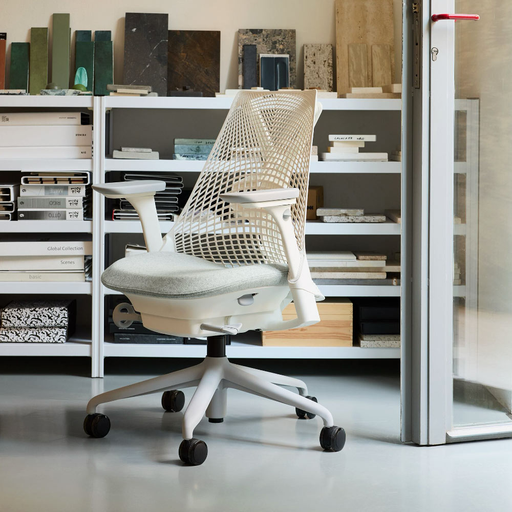 Une chaise de bureau Herman Miller Sayl blanche avec un revêtement d'assise feutré gris dans un home studio.