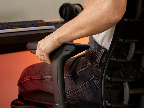Gros plan du Dr Lindsey Migliore ajustant l'accoudoir du fauteuil gaming Embody