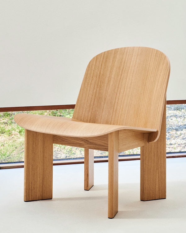 Vue de face d'un fauteuil lounge Chisel en chêne de HAY, installé dans un espace intérieur au style minimaliste.