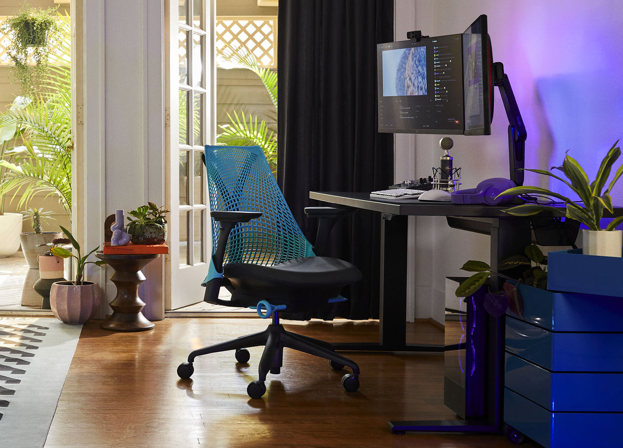 Photo de l'installation de jeu de Friskk chez elle, composée d'un fauteuil de jeu Sayl noir et bleu océan et d'un bureau de jeu Nevi noir.