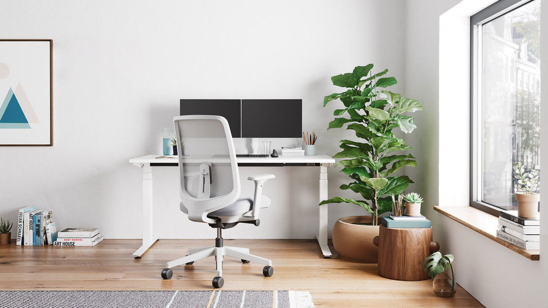 Un bureau assis-debout Nevi blanc d'Herman Miller dans un bureau à domicile lumineux.