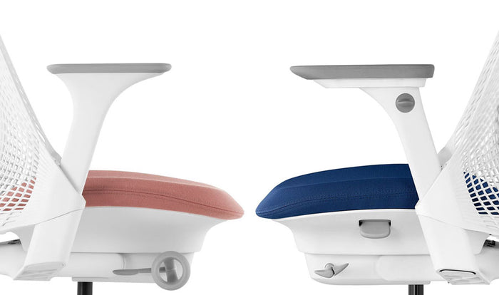 Vue latérale de deux chaises de bureau Sayl de Herman Miller se faisant face. La chaise de gauche présente l'accoudoir fixe et celle de droite l'accoudoir entièrement réglable.