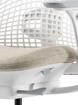 Gros plan d'une chaise de bureau Sayl beige et blanche de Herman Miller, montrant l'assise profilée.