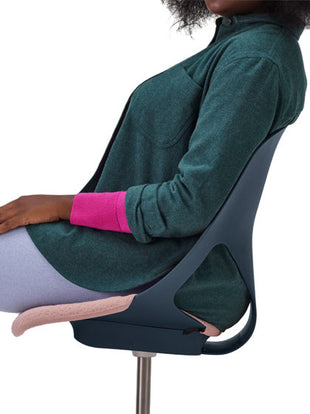 Vue latérale d'une personne assise sur une chaise de bureau Zeph bleue de Herman Miller avec une assise rose.