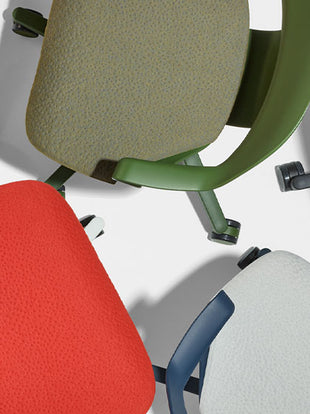 Vue de dessus de trois chaises de bureau Zeph de Herman Miller, vertes, rouges et bleues, montrant la texture des coussins d'assise.