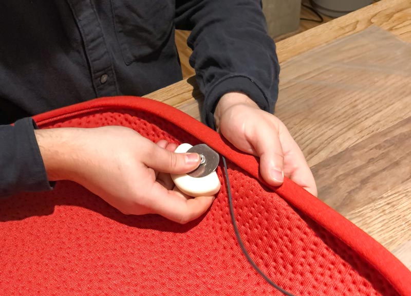 Une personne produisant un coussin d'assise en tissu rouge pour un siège de bureau Zeph d'Herman Miller.
