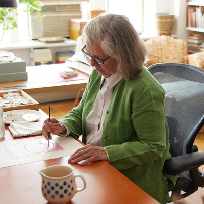 Illustrateur, peintre et auteur assis en train de peindre sur une chaise de bureau Herman Miller Aeron en graphite.