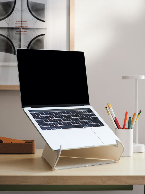 Gros plan sur un ordinateur portable posé sur un support Orpura blanc sur un bureau de bureau à domicile et une lampe de bureau blanche