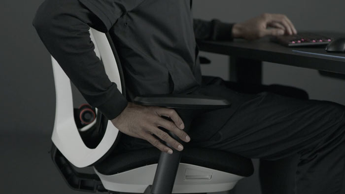 Vidéo d'une personne assise dans un fauteuil de jeu Vantum blanc et noir de Herman Miller, tendant la main à côté du fauteuil pour régler les accoudoirs.