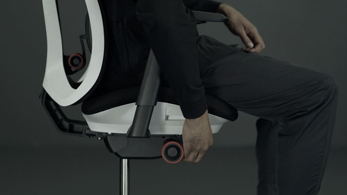 Vidéo d'une personne assise dans un fauteuil de jeu Vantum blanc et noir de Herman Miller, qui tend la main à côté du fauteuil pour régler la hauteur de l'assise.