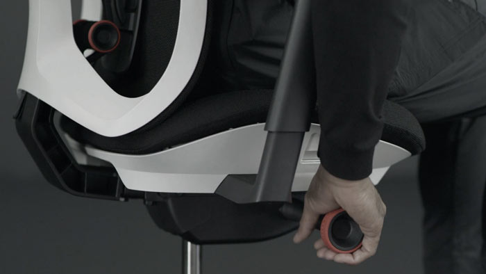 Vidéo d'une personne assise dans un fauteuil de jeu Vantum blanc et noir de Herman Miller, qui tend la main à côté du fauteuil pour régler la tension de l'inclinaison.