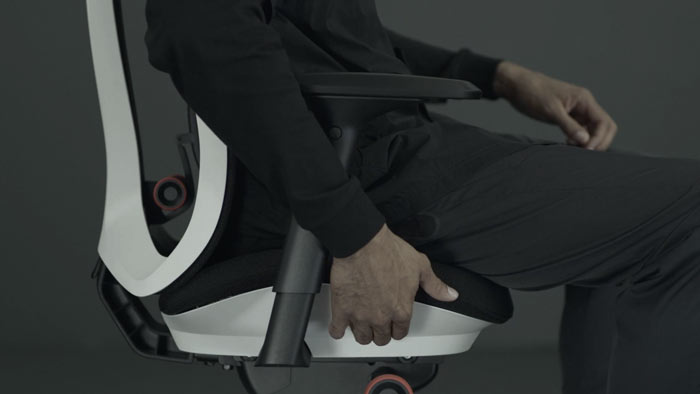 Vidéo d'une personne assise dans un fauteuil de jeu Vantum blanc et noir de Herman Miller, qui tend la main à côté du fauteuil pour régler la profondeur de l'assise.