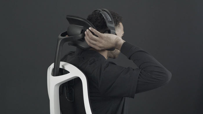 Vidéo d'une personne assise dans un fauteuil de jeu Vantum blanc et noir de Herman Miller, qui tend la main derrière le fauteuil pour régler l'appui-tête.