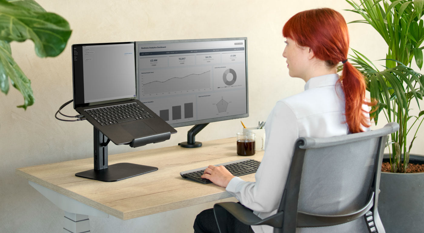 Une femme utilisant un bureau à domicile avec un bureau Nevi, une chaise Setu et un support pour ordinateur portable Lana.