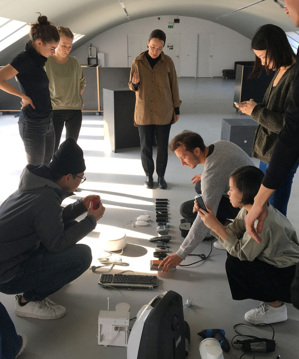Photo des designers de Studio 7.5 regardant divers petits appareils électroniques posés sur le sol