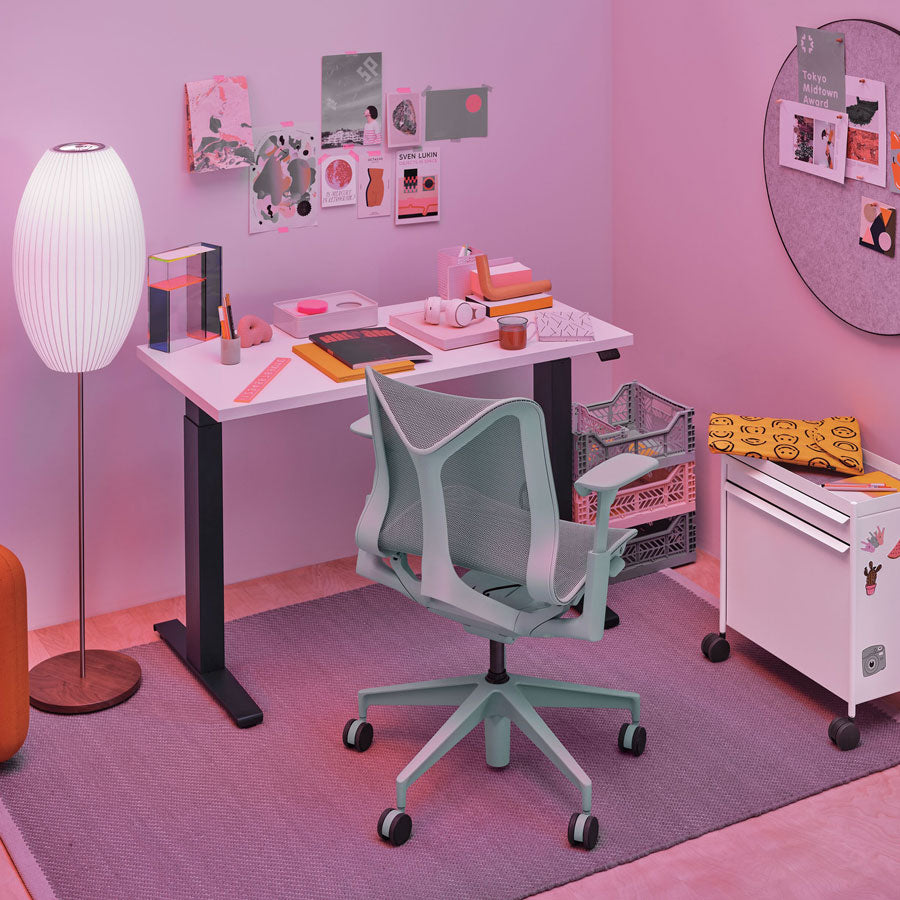 Aménagement de bureau à domicile avec une chaise de bureau Cosm à dossier bas en gris glacier devant un bureau assis-debout Nevi avec des pieds noirs et un plateau blanc