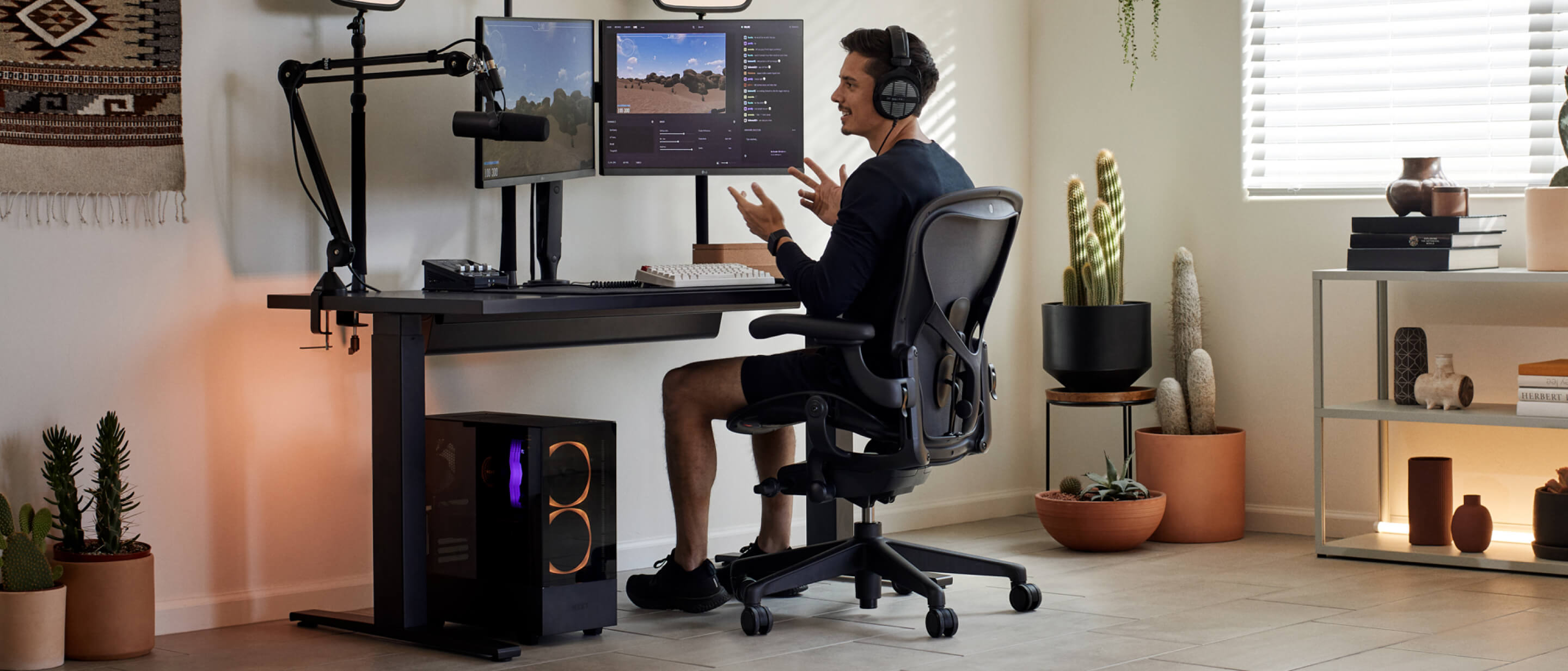 Le joueur Xaryu, les mains en l'air, jouant à un jeu sur son installation Herman Miller, composé d'un fauteuil gaming Aeron, d'un bureau gaming Nevi et de deux bras supports pour moniteur Ollin
