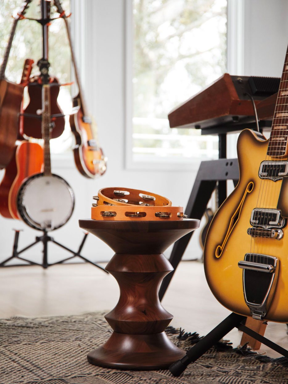 Photo d'un tabouret en bois Herman Miller Hew avec des tambourins et diverses guitares et banjos