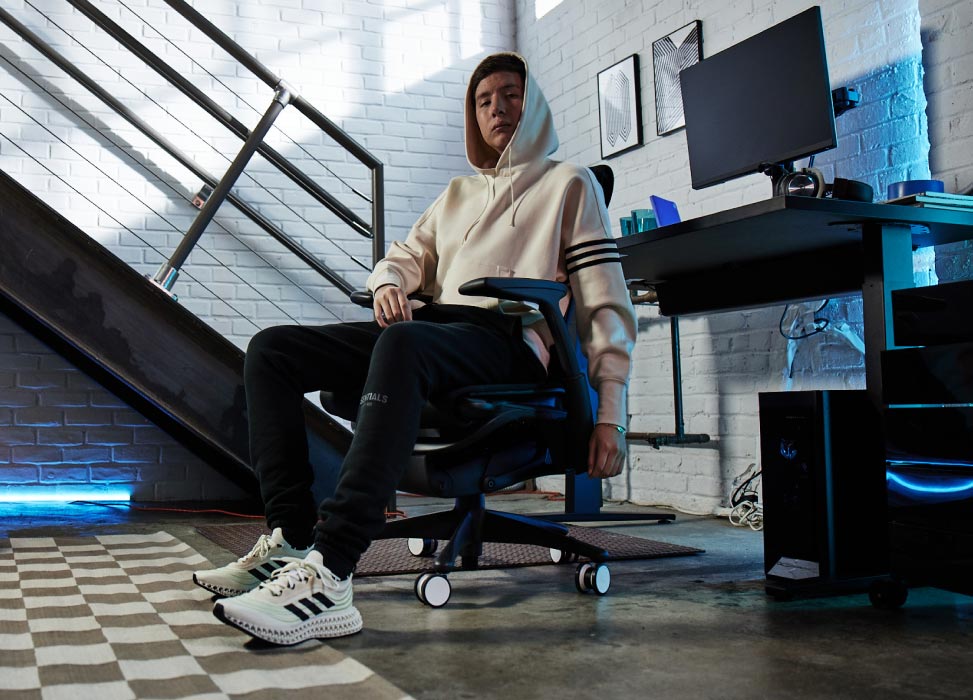 Photo de Jelty, membre de l'équipe G2 Esports, assis sur une chaise G2 Embody, dos tourné vers son installation de jeu comprenant un bureau de jeu Nevi noir et des écrans Ollin