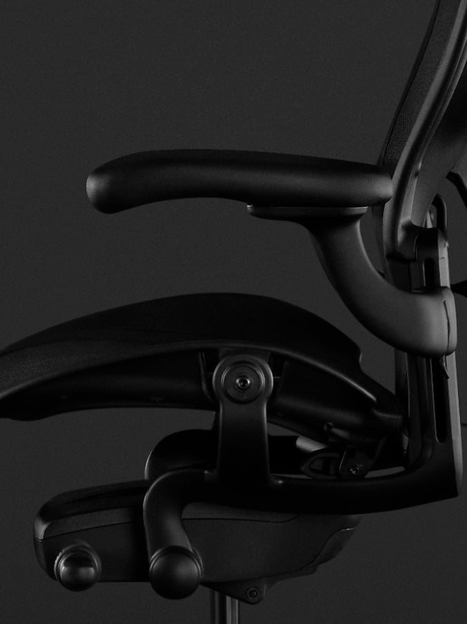 Vue latérale d'un fauteuil de jeu Aeron noir de Herman Miller, montrant les accoudoirs entièrement réglables.