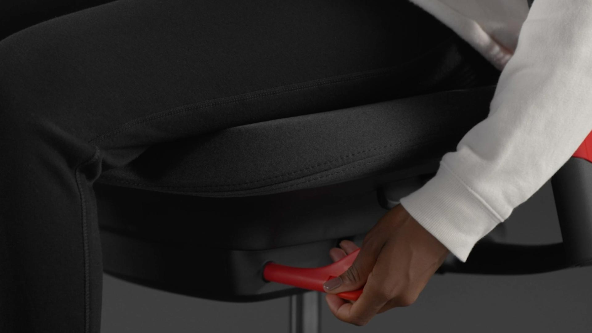 Vidéo d'une personne assise dans un fauteuil de jeu Sayl rouge et noir de Herman Miller, qui tend la main à côté du fauteuil pour régler l'inclinaison vers l'avant.