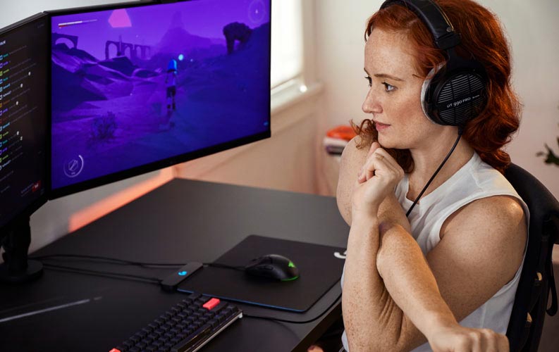 Lindsey Migliore, médecin spécialisée dans l'e-sport, devant une installation de jeu avec deux écrans sur des bras pour moniteur Ollin.