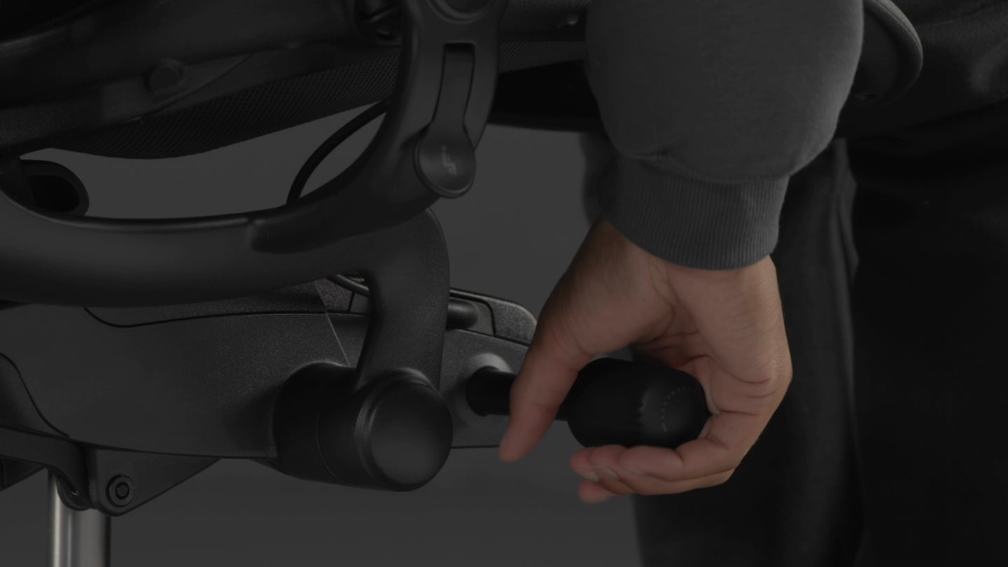 Vidéo d'une personne assise dans un fauteuil de jeu Aeron noir de Herman Miller, qui tend la main à côté du fauteuil pour régler la tension de l'inclinaison.