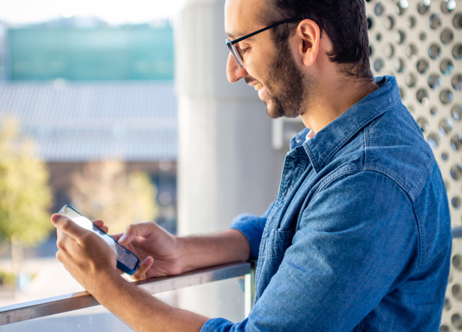 Photo d'Ali Abdaal à la fenêtre de son domicile, regardant son téléphone