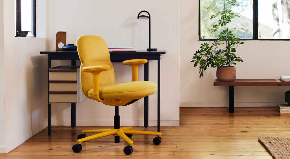Un fauteuil de bureau Asari jaune de Herman Miller, recouvert de tissu Clarion Luce de Maharam, avec un bureau Mode et une lampe Marselis.
