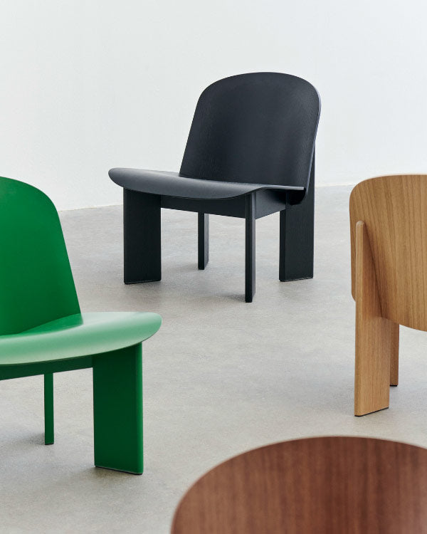 Photo de groupe de quatre fauteuils Chisel de HAY, présentant les différentes options de couleurs. Disposés dans un environnement intérieur avec sol en béton et murs blancs.