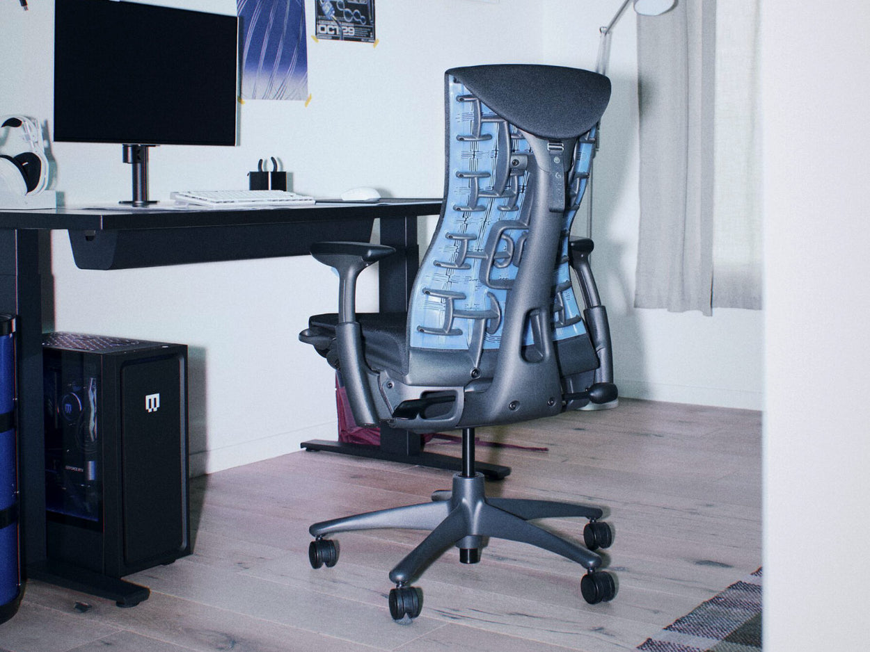 Un siège gaming ergonomique Herman Miller Embody noir et bleu cyan, dans un setup de gaming sur PC avec un bureau Nevi noir
