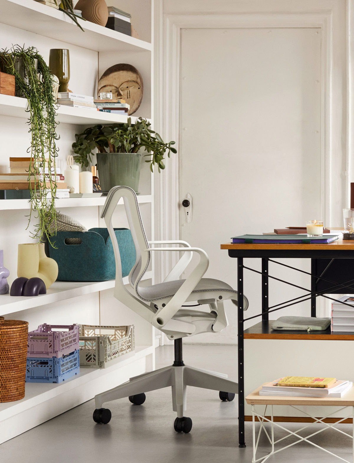 Bureau à domicile avec un siège Cosm à dossier bas en blanc minéral devant des étagères verticales avec des caisses de rangement Hay et divers objets décoratifs