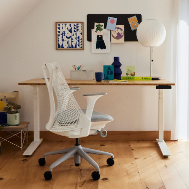 Bureau à domicile avec un siège de bureau Sayl en blanc et gris devant un bureau assis-debout Jarvis en blanc avec plateau en bambou
