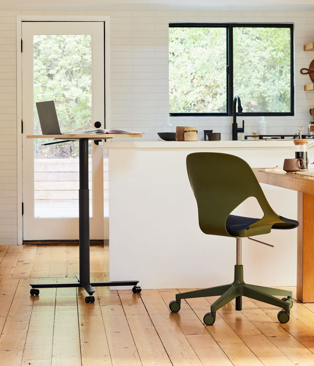 Scène de bureau à domicile dans une cuisine avec une table de travail assis-debout Passport avec un plateau en chêne, un fauteuil de bureau Zeph en olive avec un coussin d'assise bleu nuit à la table de cuisine