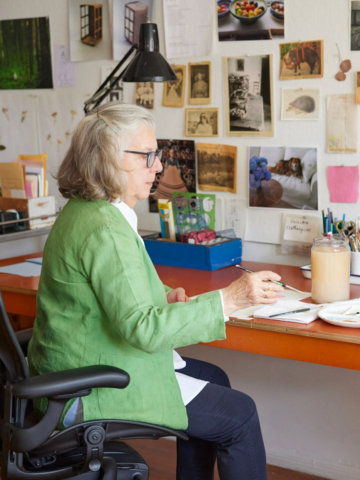 Photo d'un illustrateur, peintre et auteur assis à son bureau en train de peindre sur une chaise de bureau Aerong en graphite