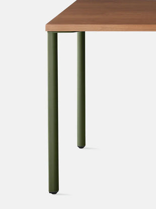 Gros plan de face d'un bureau OE1 vert et noyer de Herman Miller, montrant le design des pieds en forme de goutte.
