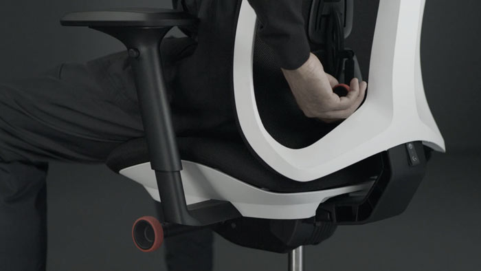 Vidéo d'une personne assise dans un fauteuil de jeu Vantum blanc et noir de Herman Miller, qui tend la main derrière le fauteuil pour régler le dossier.