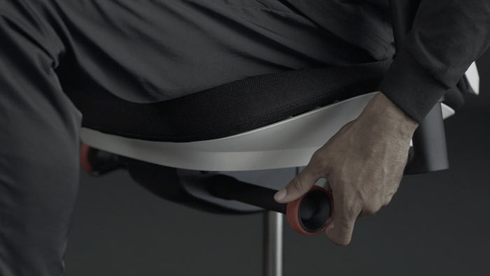 Vidéo d'une personne assise dans un fauteuil de jeu Vantum blanc et noir de Herman Miller, qui tend la main à côté du fauteuil pour régler le limiteur d'inclinaison.