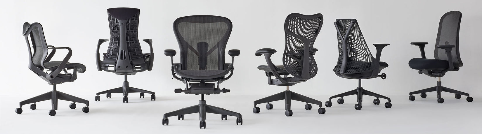 Alignement de chaises de bureau Herman Miller sous différents angles, toutes en graphite, avec Cosm à dossier bas, Aeron, Mirra 2 et Lino
