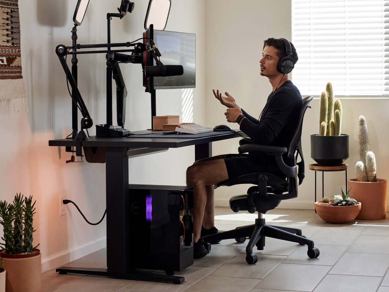 Le joueur Xaryu assis devant son installation de jeu à domicile, avec un fauteuil de jeu Aeron graphite, un bureau de jeu Nevi et deux bras supports pour moniteur Ollin