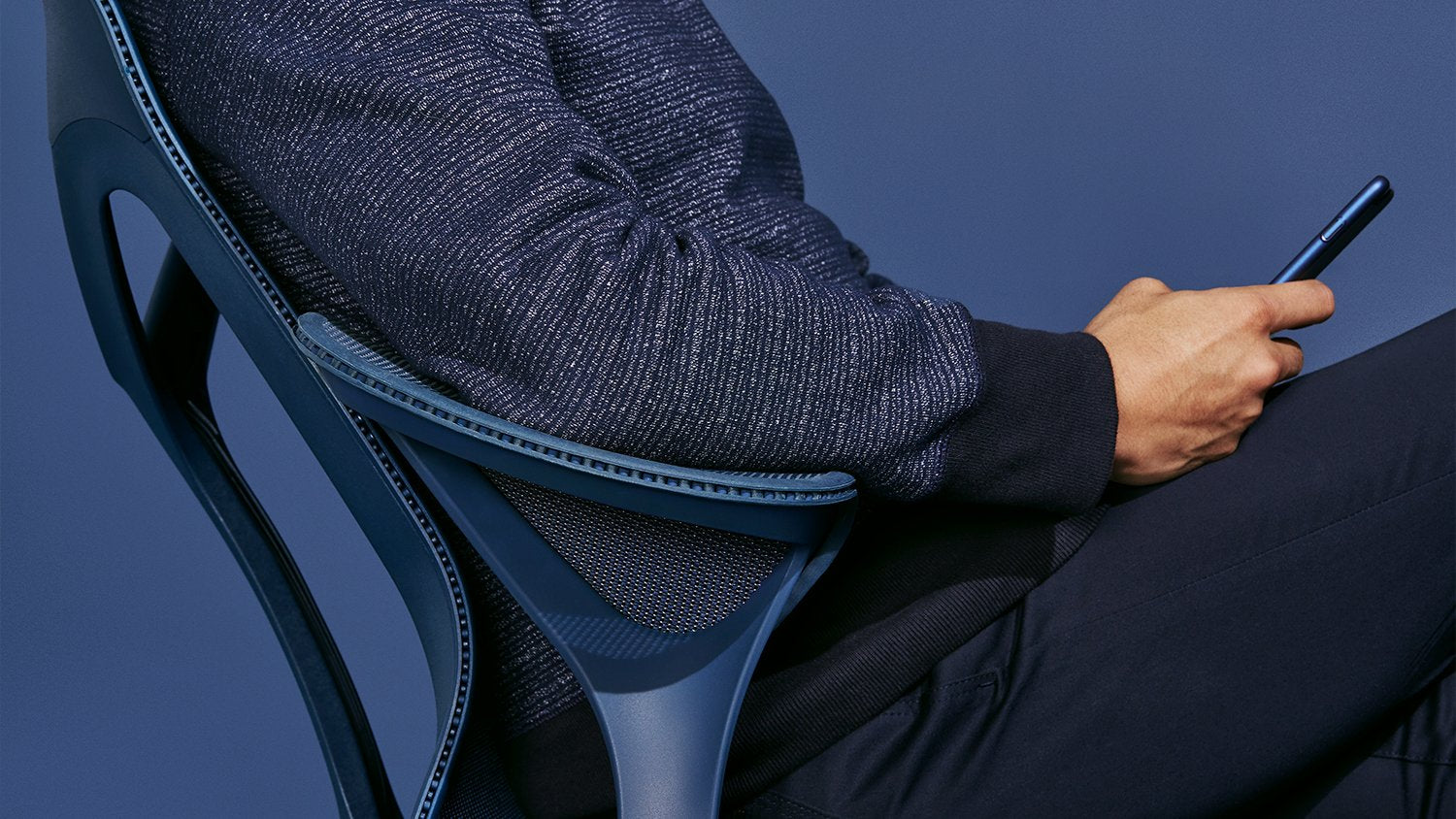A close up of a blue Cosm chair in front of a blue back drop