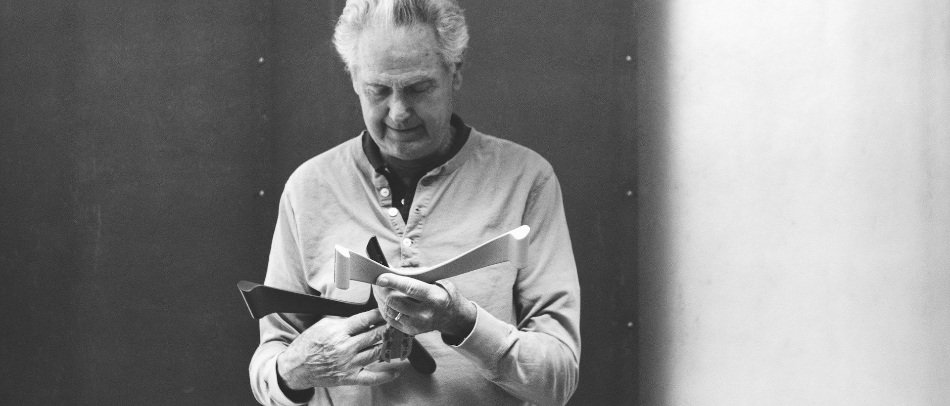 Photographie  en noir et blanc de Don Chadwick tenant des composants de siège